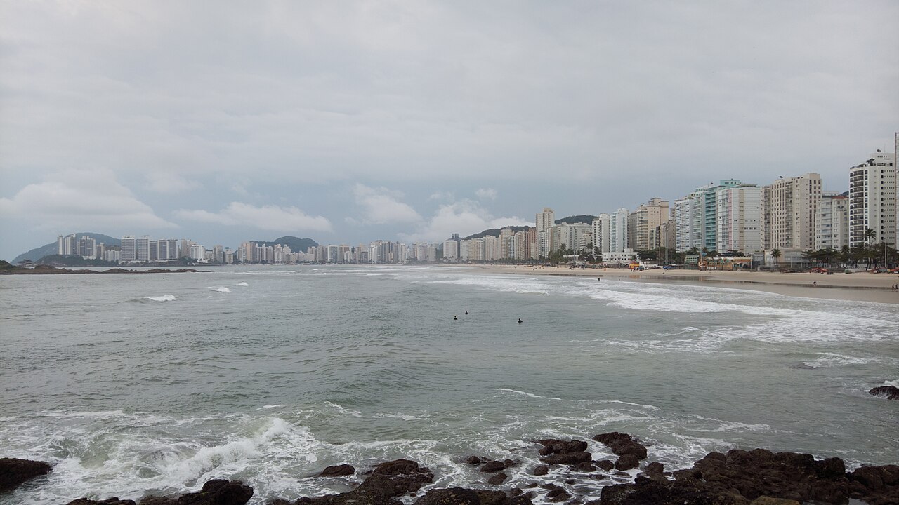 Faixa de areia, mar e edifícios na Praia de Pitangueiras, no Guarujá